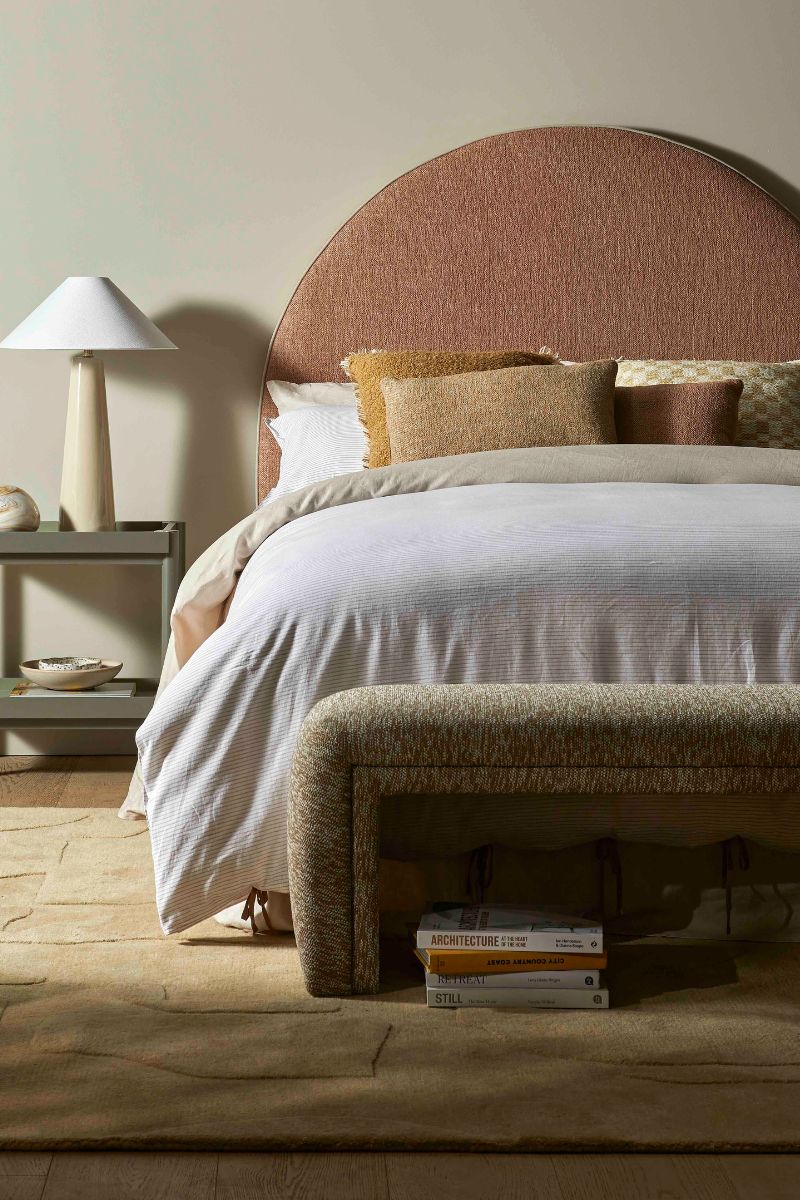A beautifully made bed with books and lamps next to it