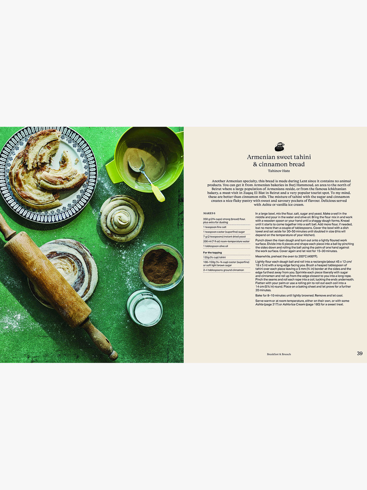 An open cookbook spread showing a recipe for Armenian sweet tahtni & cinnamon bread. The left page features a styled flat-lay photograph of a sliced bread with cinnamon swirls, a rolling pin, bowls, and flour on a green surface.
