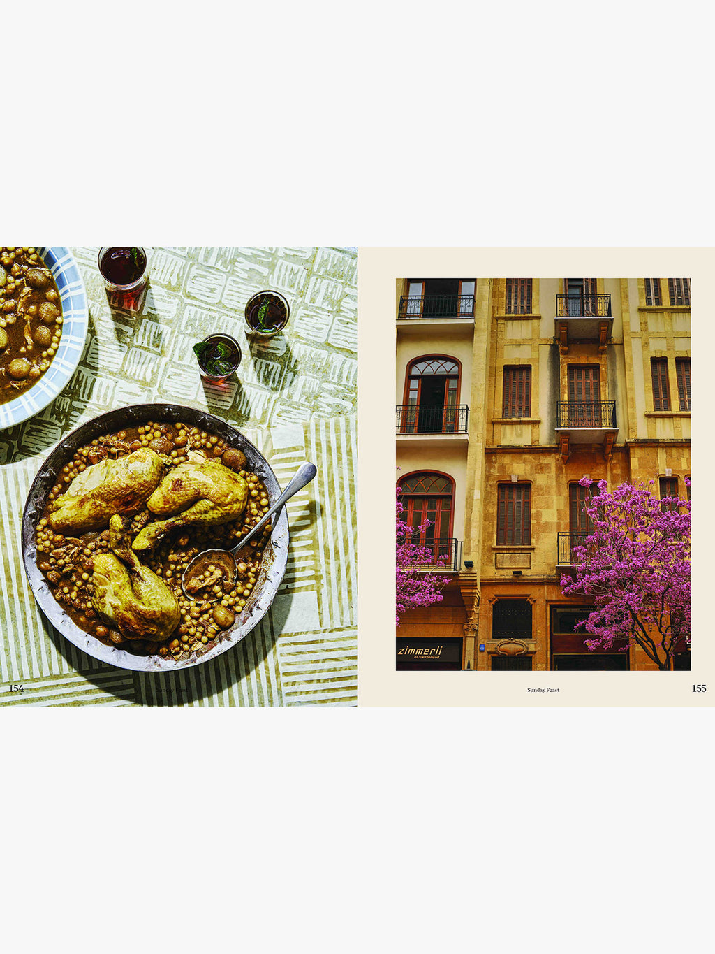 A two-page spread from a magazine or cookbook, showing a plated chicken and chickpea dish on a patterned tablecloth on the left, and a street scene with yellow buildings and pink-purple trees on the right.